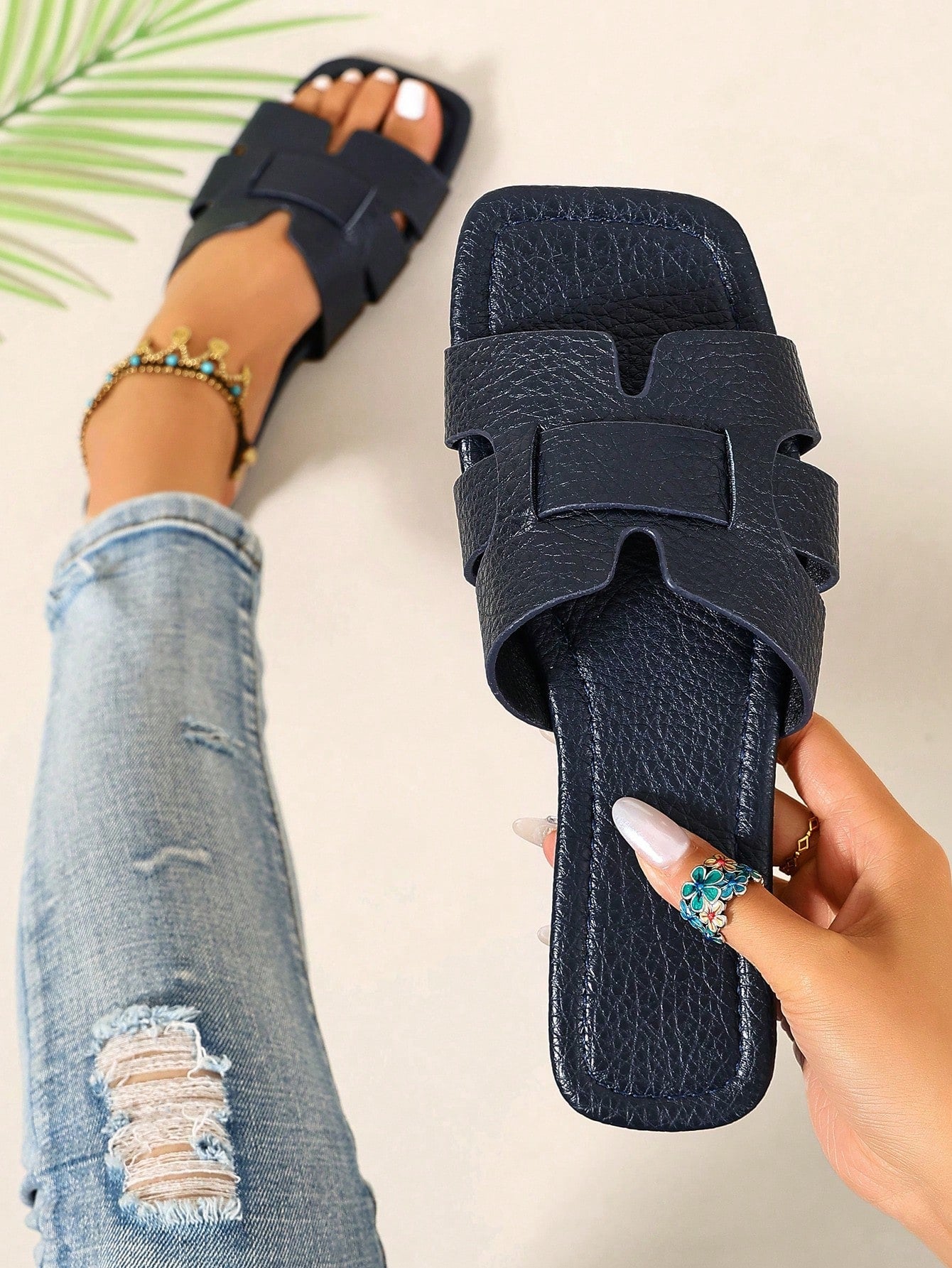 Pair of women’s open-toe flat slide sandals with an H-shaped strap, braided and embossed details, and a minimalist slip-on design suitable for casual outdoor wear.