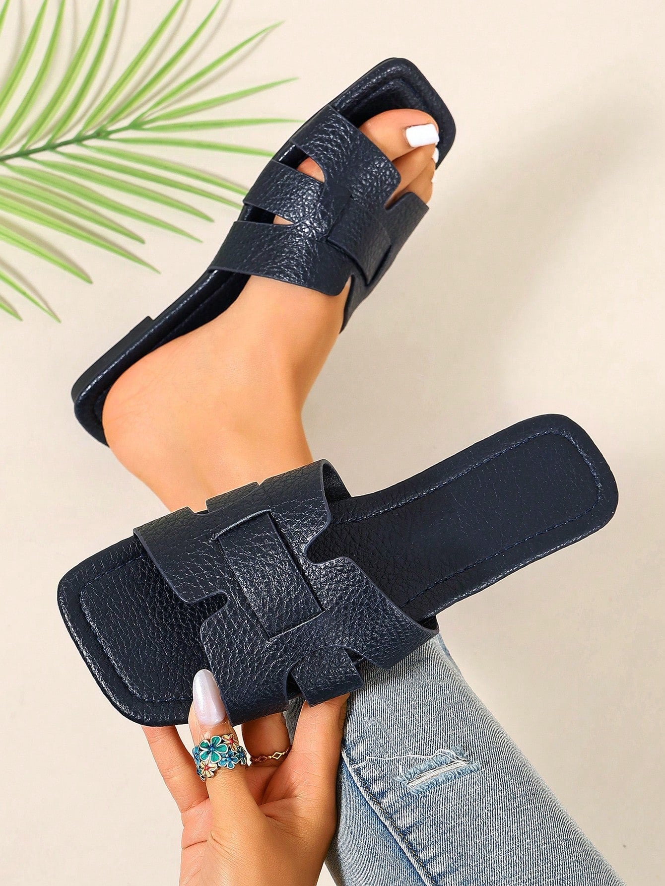 Pair of women’s open-toe flat slide sandals with an H-shaped strap, braided and embossed details, and a minimalist slip-on design suitable for casual outdoor wear.