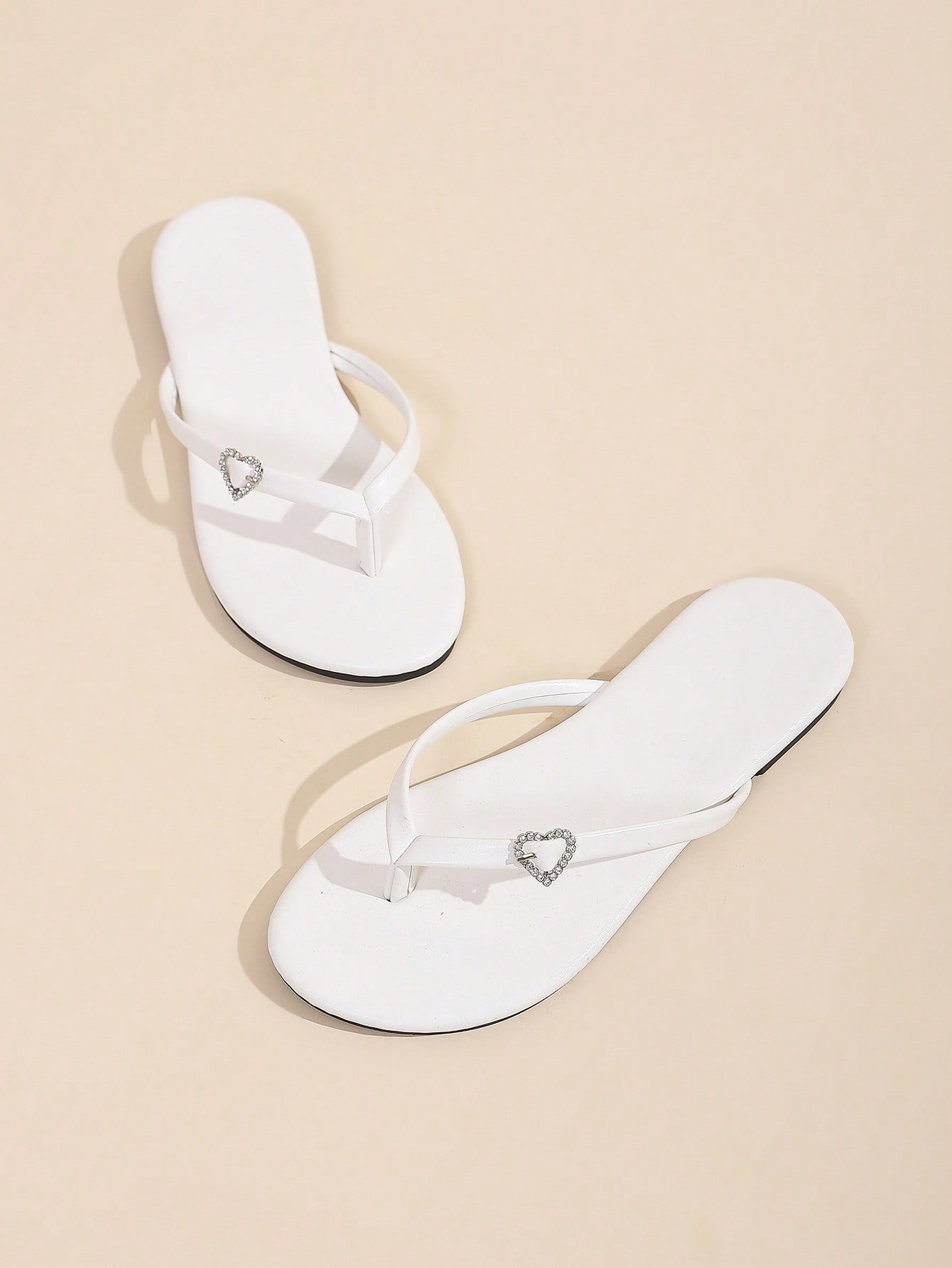 Women's black flat slide sandals with toe post design, textured PU leather straps, and rhinestone heart decoration.