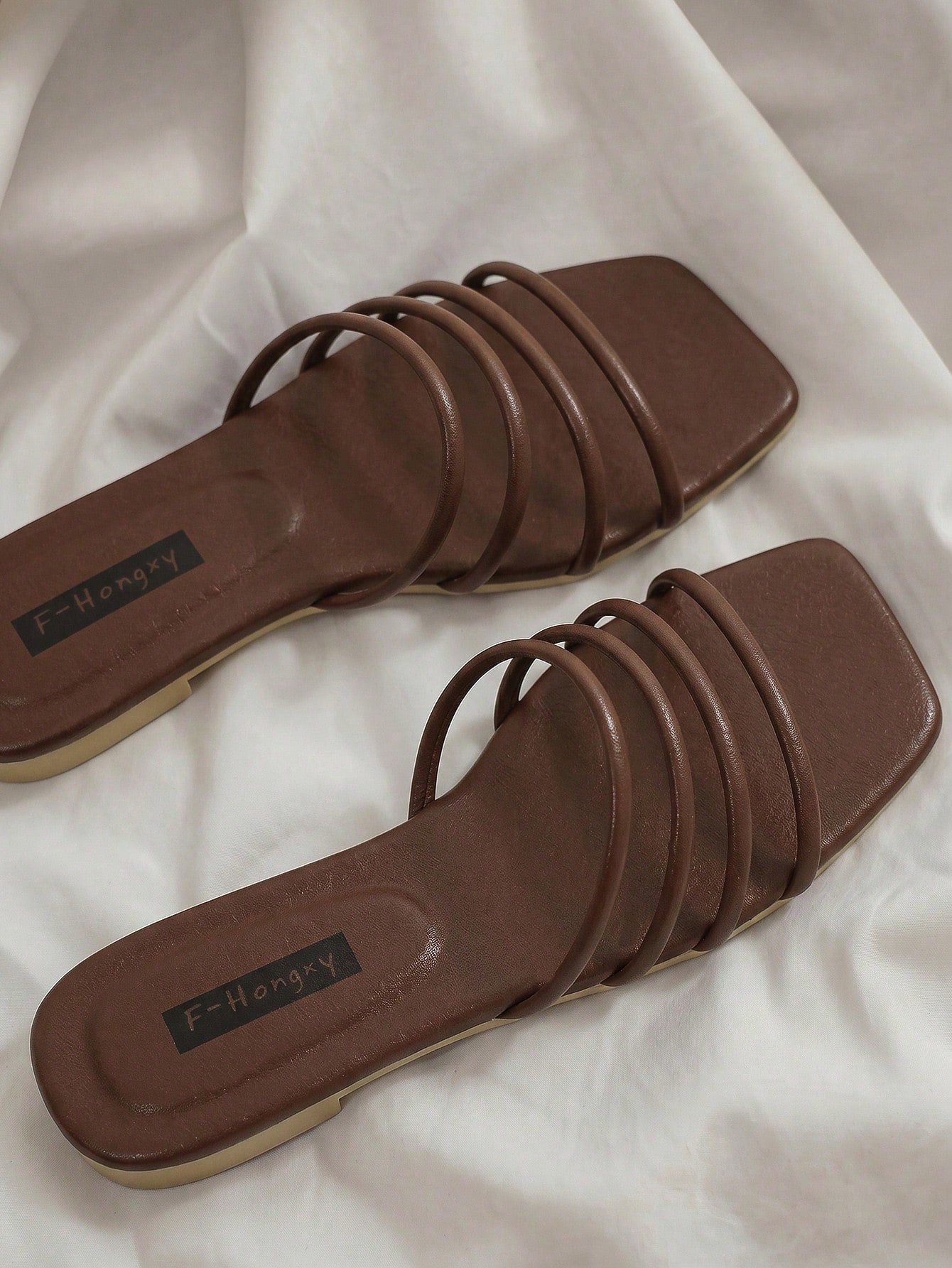 Women's slip-on flat slide sandals with bow tie decor, textured plain upper, and open toe.