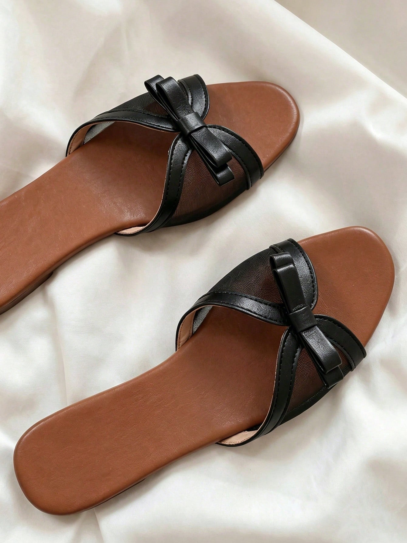 Women's flat slip-on slide sandals with textured PU leather look, bow detail on the upper, and toe-post design for casual vacation and beach wear.