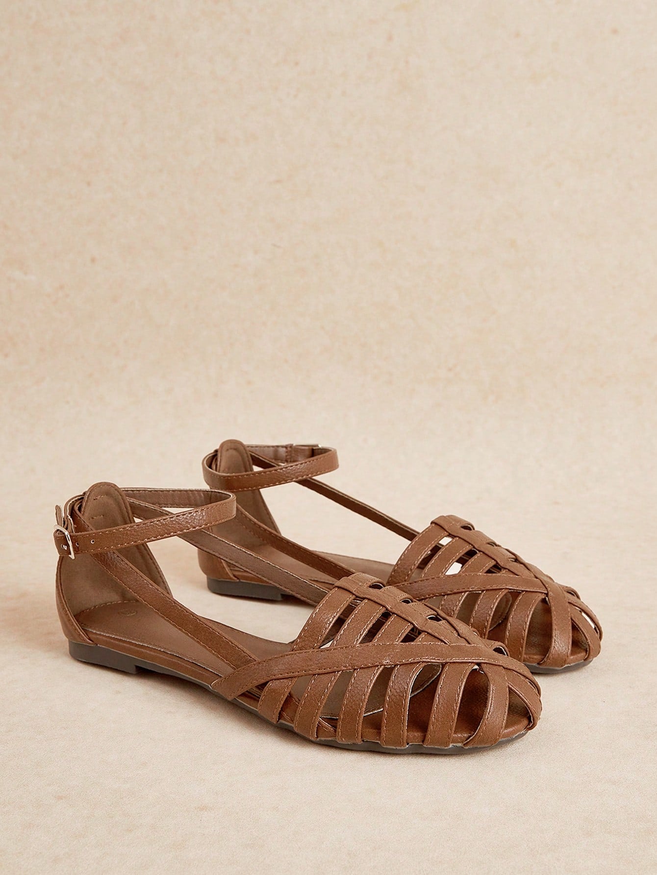 Women's flat gladiator sandals featuring a hollow-out multi-strap woven design and ankle strap style, with striped pattern and casual beach vacation look.