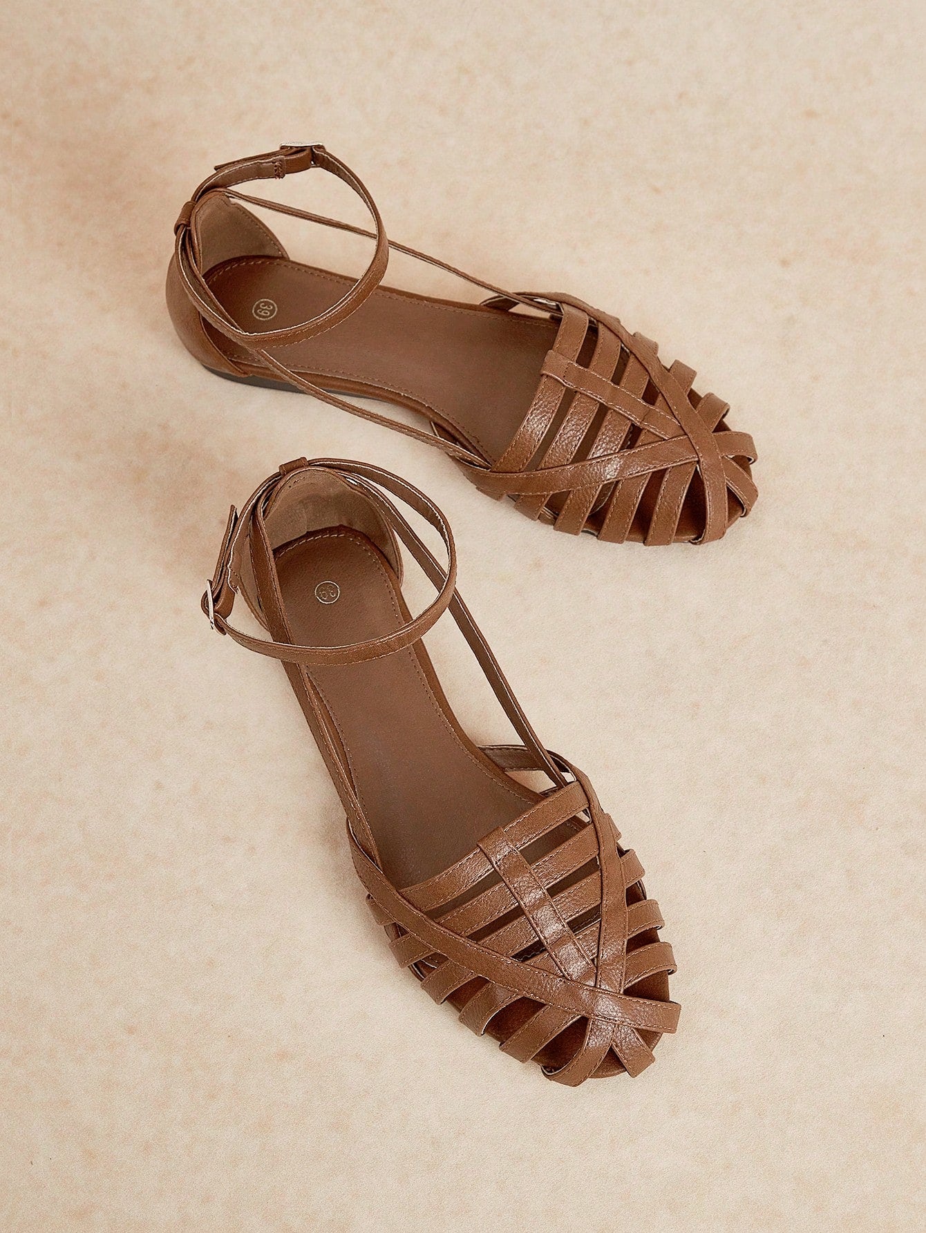 Women's flat gladiator sandals featuring a hollow-out multi-strap woven design and ankle strap style, with striped pattern and casual beach vacation look.