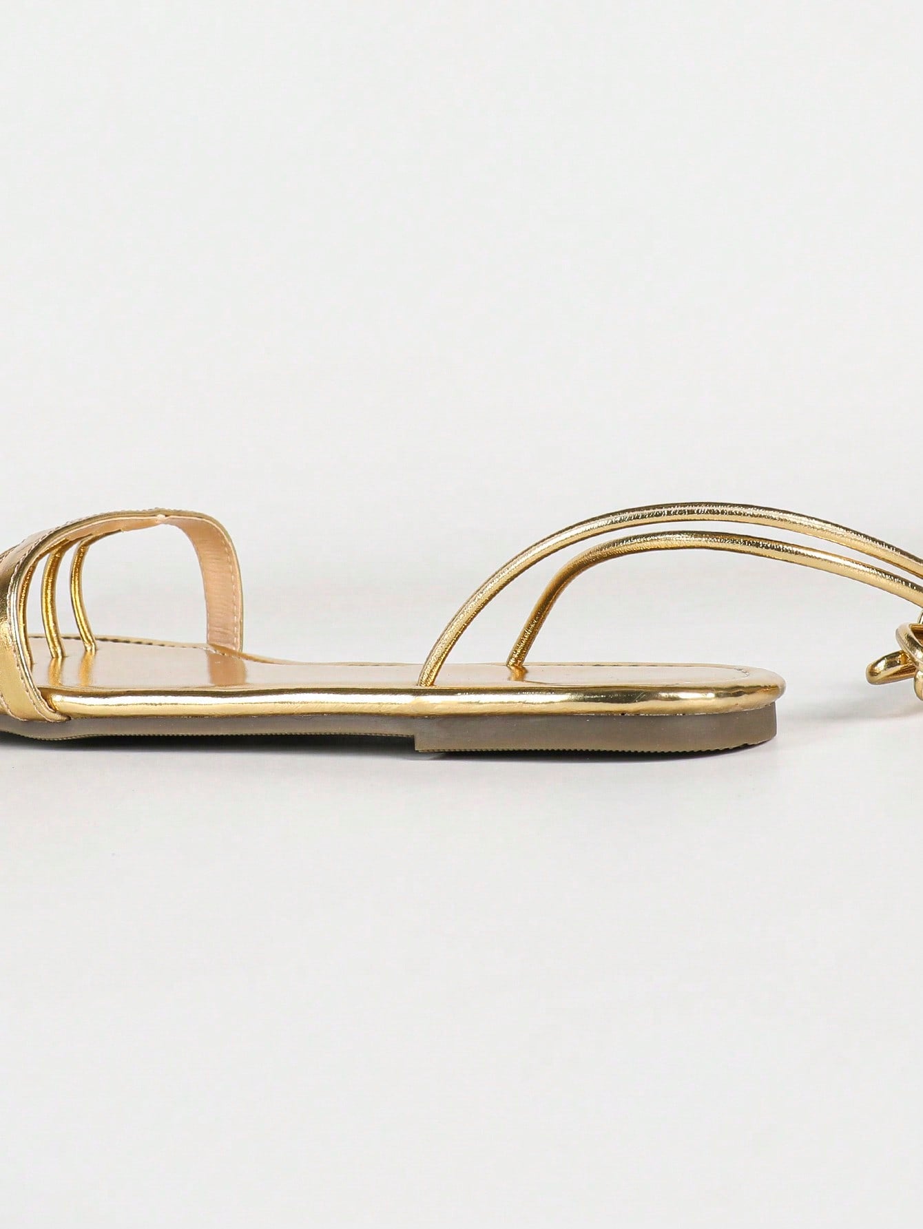 Women's gold flat sandals with metal accent detail, strappy lace-up design, and toe post thong style.
