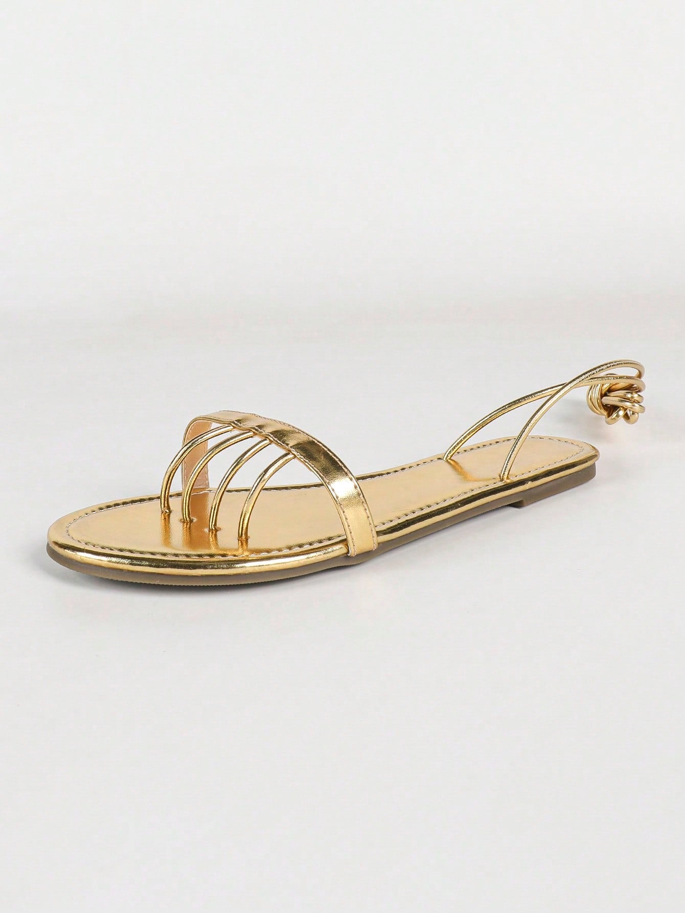 Women's gold flat sandals with metal accent detail, strappy lace-up design, and toe post thong style.
