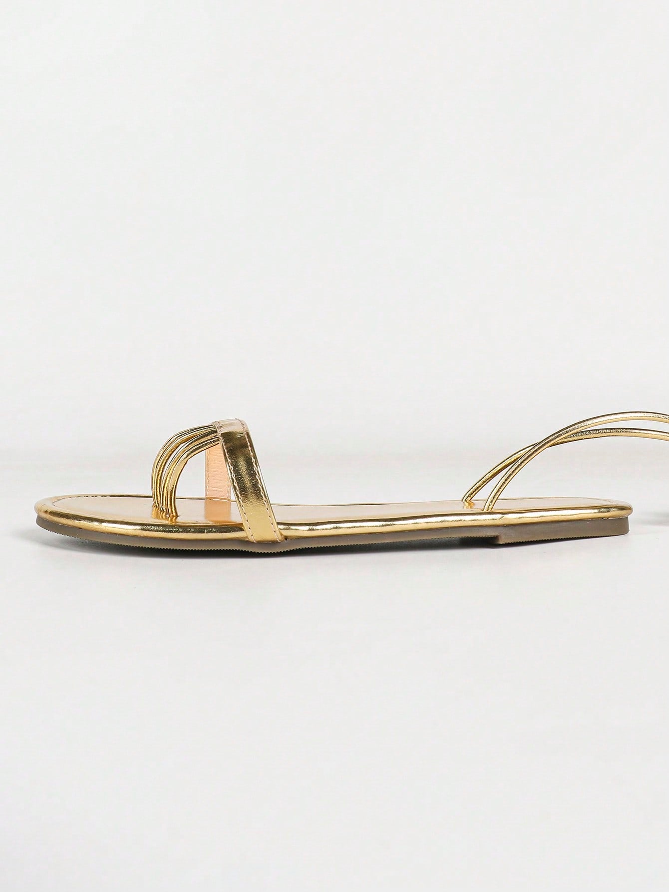 Women's gold flat sandals with metal accent detail, strappy lace-up design, and toe post thong style.