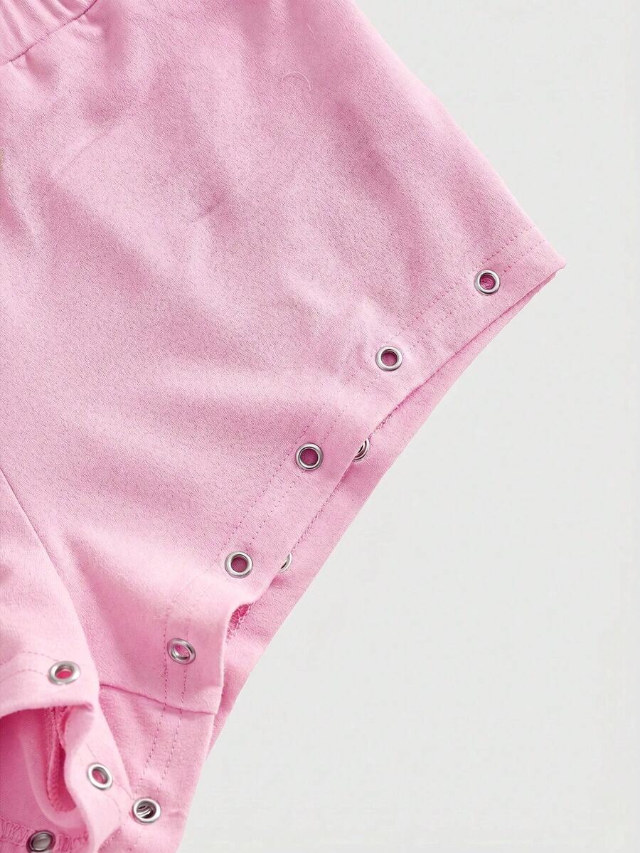 Women's two-piece outfit with an asymmetric neck studded grommet crop top and super low-rise mini shorts