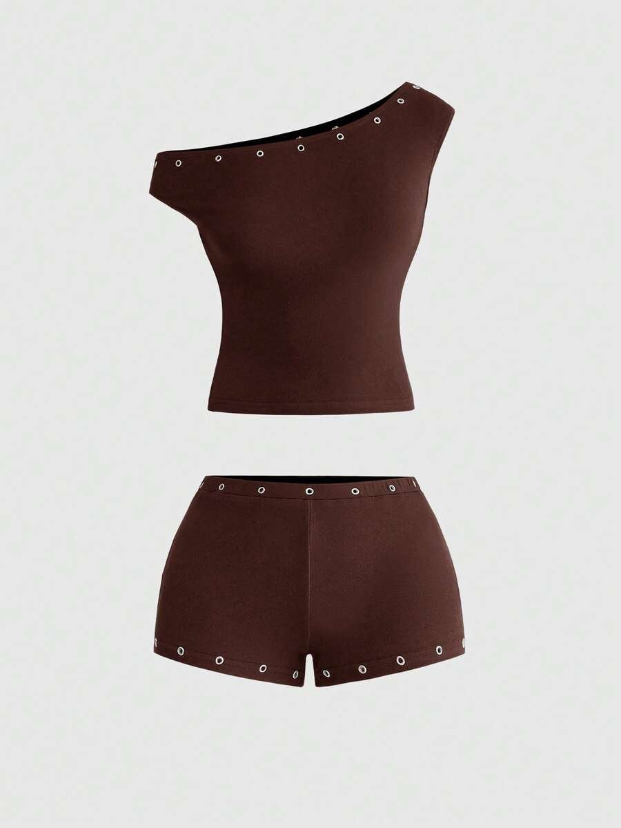 Women's two-piece outfit with an asymmetric neck studded grommet crop top and super low-rise mini shorts