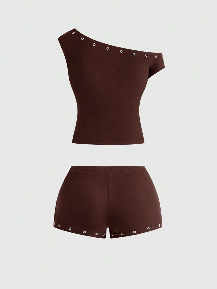 Women's two-piece outfit with an asymmetric neck studded grommet crop top and super low-rise mini shorts