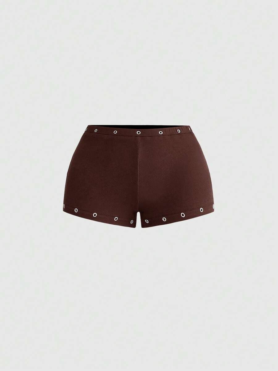 Women's two-piece outfit with an asymmetric neck studded grommet crop top and super low-rise mini shorts