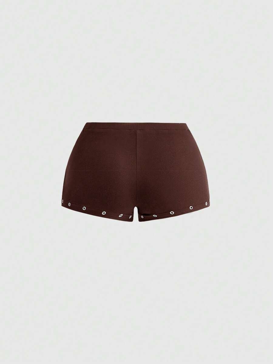 Women's two-piece outfit with an asymmetric neck studded grommet crop top and super low-rise mini shorts
