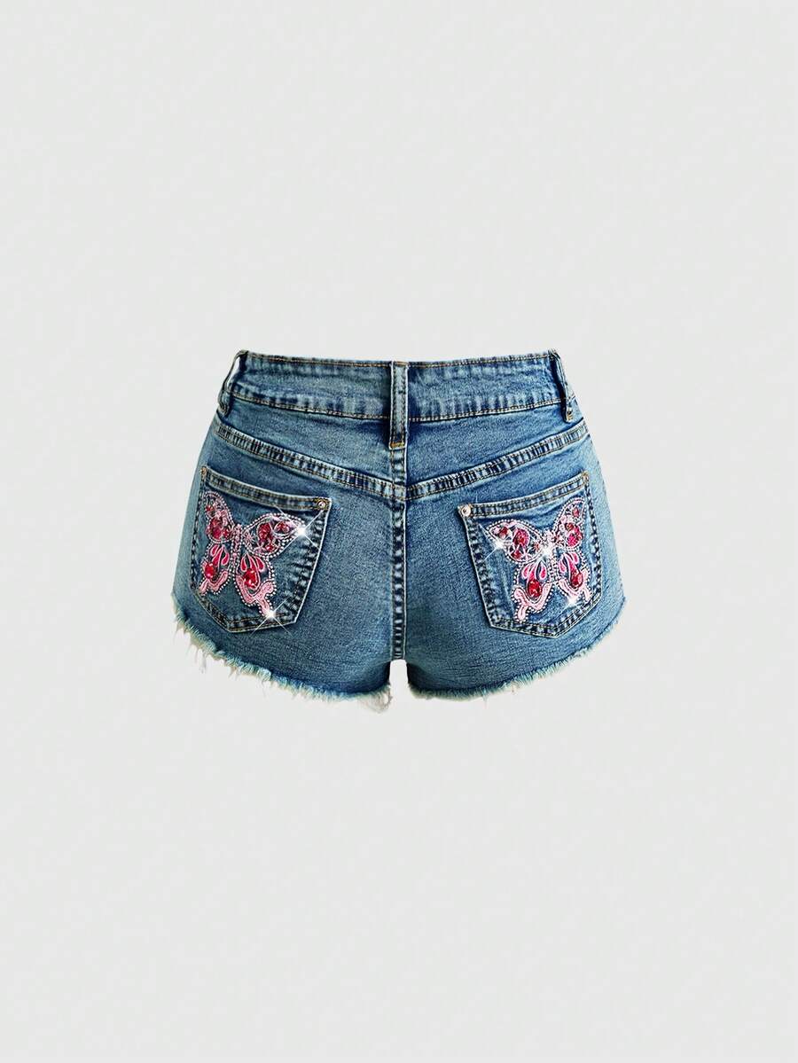Women's medium wash low waist shorts with butterfly embroidery, rhinestone embellishments, zipper fly, and skinny fit