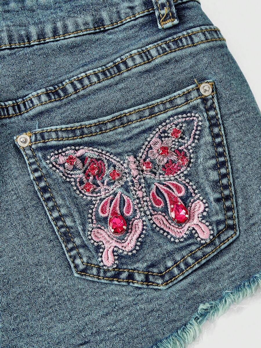 Women's medium wash low waist shorts with butterfly embroidery, rhinestone embellishments, zipper fly, and skinny fit