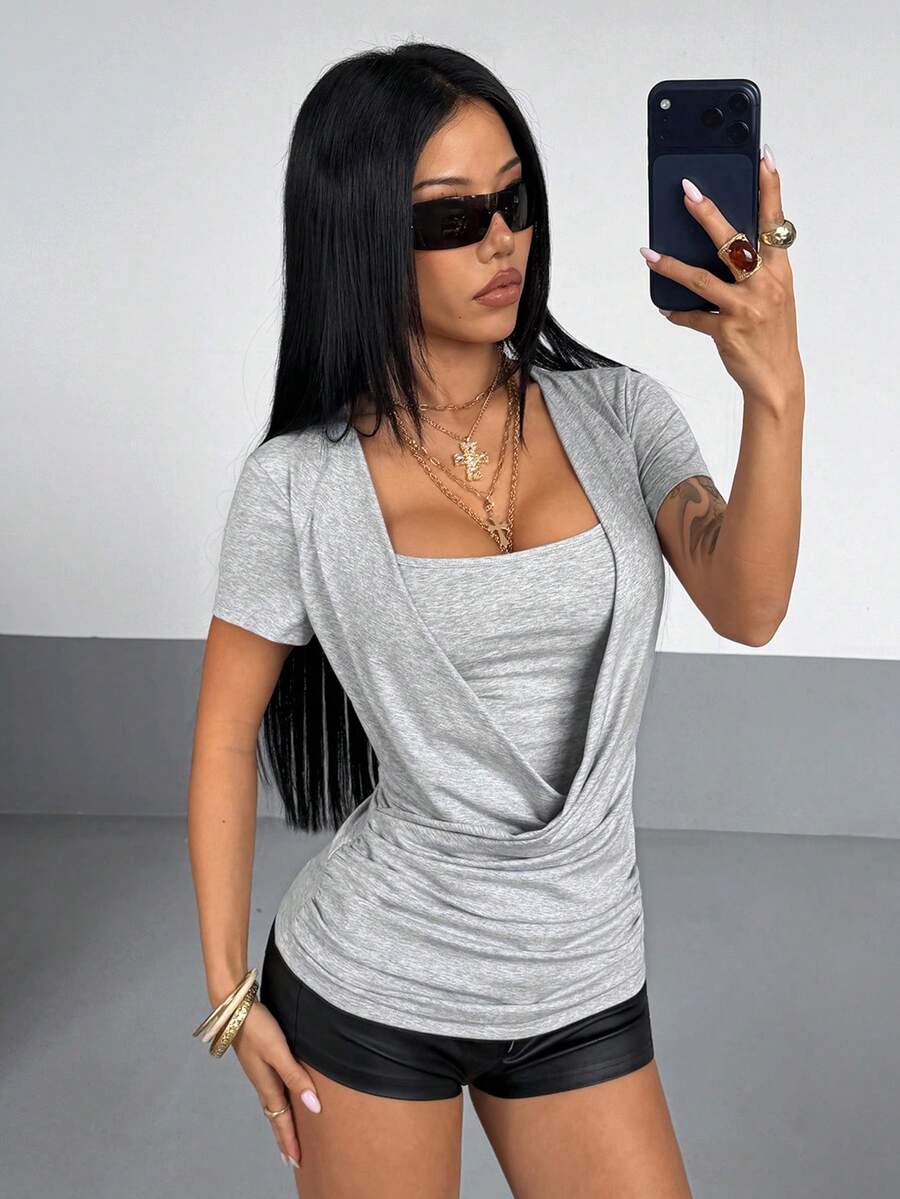 Women's slim fit short sleeve T-shirt with a low cut cowl neck, ruched details, and ruffle hem in a casual Y2K-inspired streetwear style.